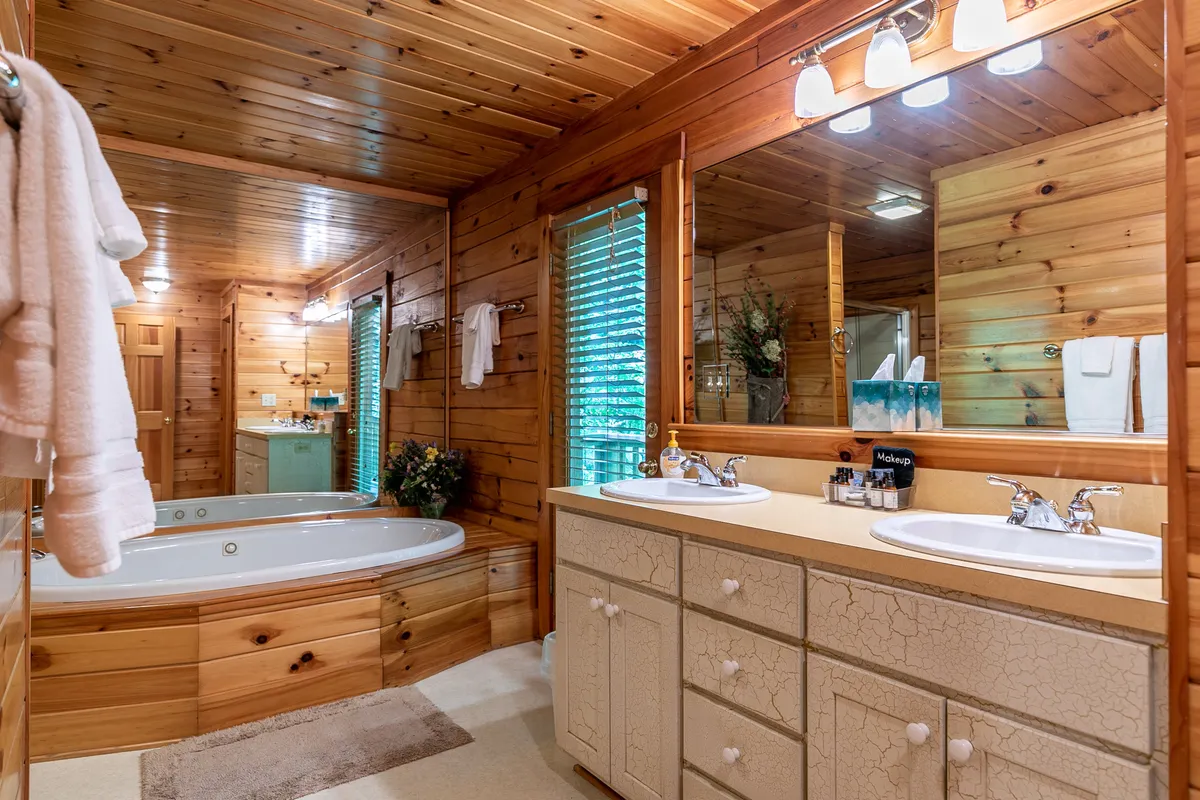 A spa-inspired ensuite bathroom with a luxurious jacuzzi soaking tub, double vanity with dual sinks, elegant wooden paneling, and blue accent touches that evoke a calm, spa-like atmosphere. The layout showcases ample space for both relaxation and convenience.