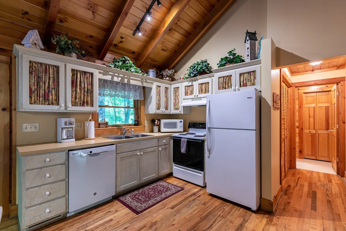 This image shows the kitchen area with well-organized cabinets, a spacious countertop, a sink, modern appliances, and a window that lets in natural light. The setup invites culinary inspiration and highlights the functionality and style of the kitchen.